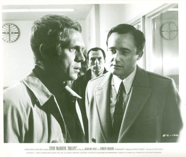 Frank Bullitt (Steve McQueen) talks to politician 
Walter Chalmers (Robert Vaughn) at the airport as Detective Delgetti (Don Gordon) watches on from the background.